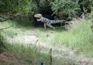 Veloceraptor aus Kunststoff steht im Gebüsch