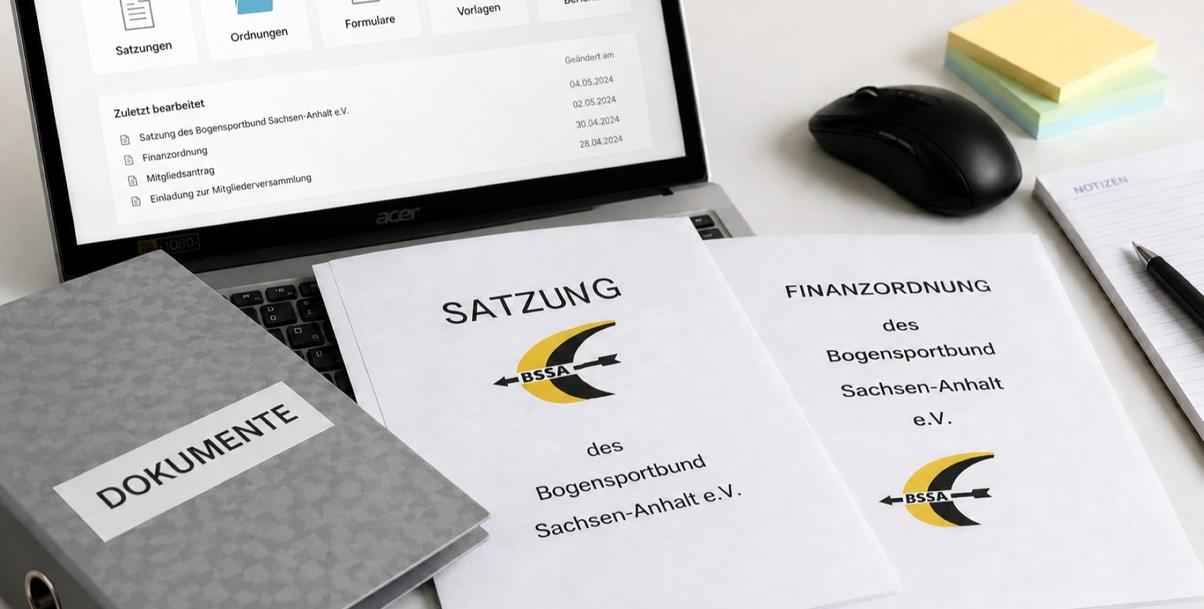 Dokumente liegen auf einem Schreibtisch vor einem Laptop