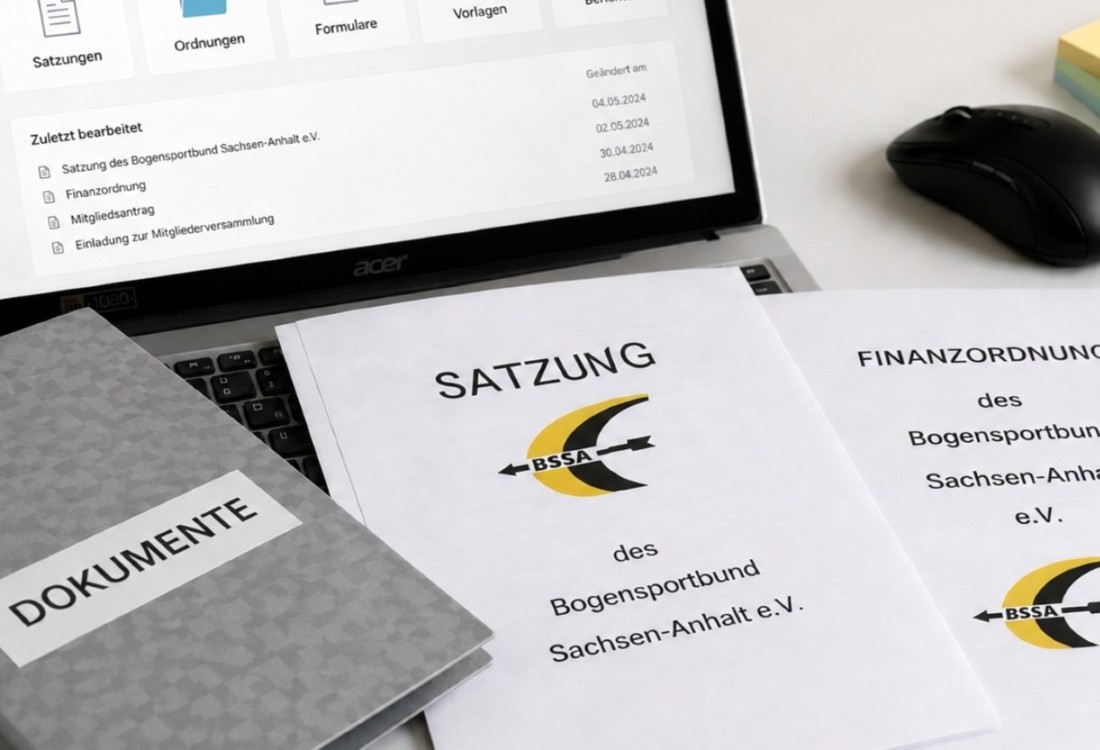 Dokumente liegen auf einem Schreibtisch vor einem Laptop