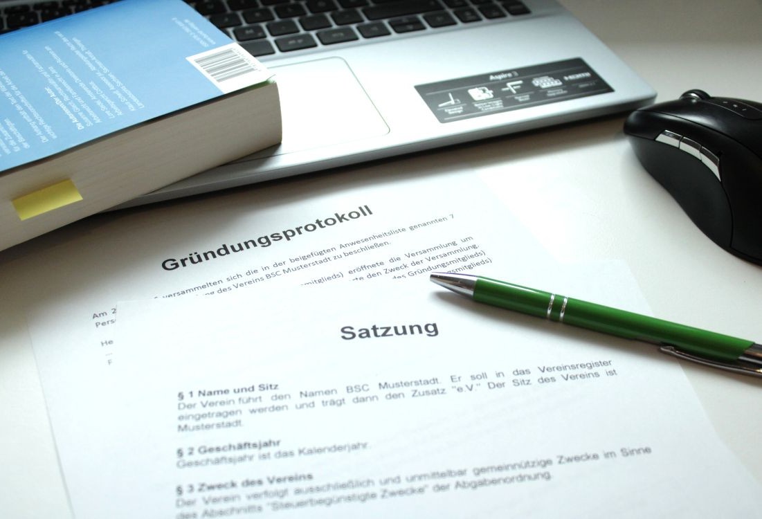 Eine Satzung und ein Gründungsprotokoll liegen vor einem Laptop